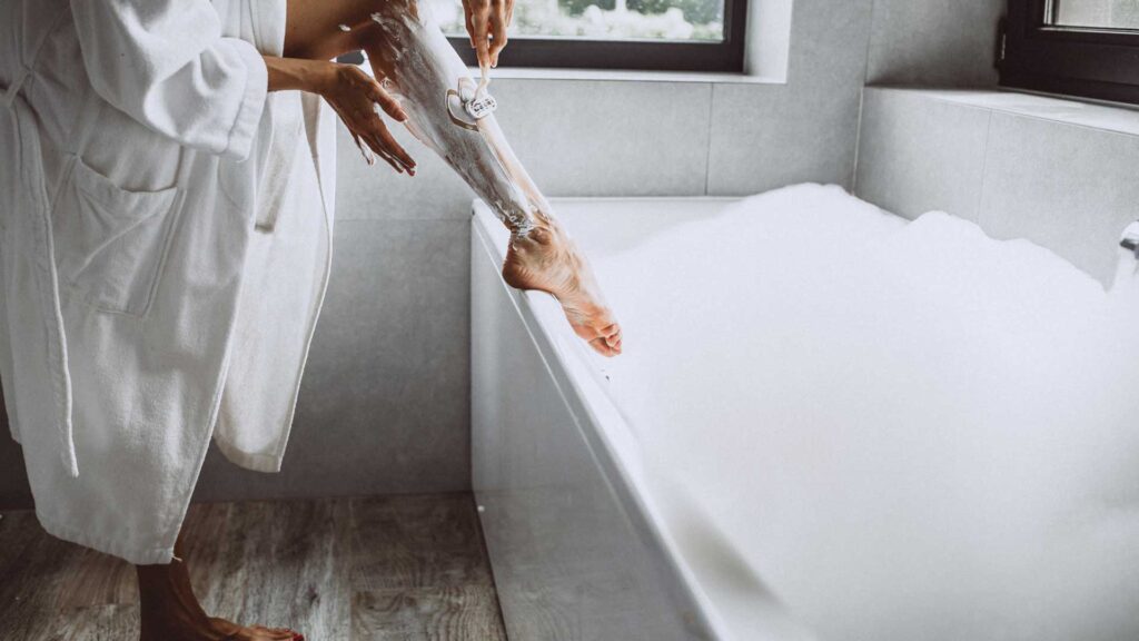 Woman washing legs at home in bathroom.