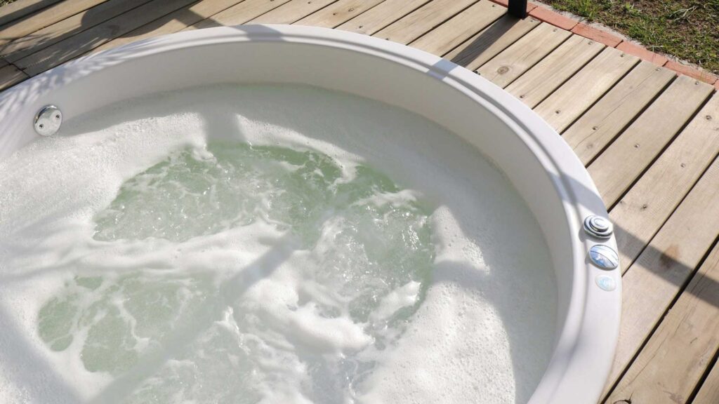 small spa hot tub in wooden floor in garden.