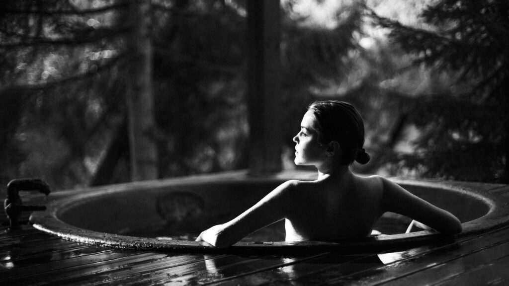 young girl relaxing in hot tub in forest.
